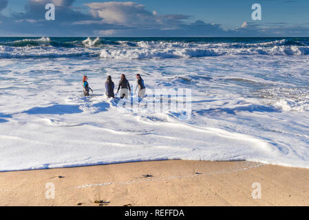 Menschen in Neoprenanzüge im Meer bei Fistral Beach in Newquay Cornwall. Stockfoto