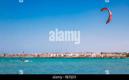 Ägypten, Hurghada, 30. November 2017: Der kiteboarder Gleiten über das Rote Meer Oberfläche. Der rote Drachen Segelfliegen in den klaren, blauen Himmel. Hurghada Hotels bac Stockfoto