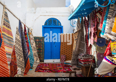 Traditionelle tunesische Teppiche hängen an den blauen Wänden in Sidi Bou Said. Tunesien und Nordafrika. Stockfoto