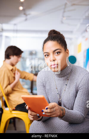 Die junge Frau mit einem Tablett in den orange Fall Stockfoto