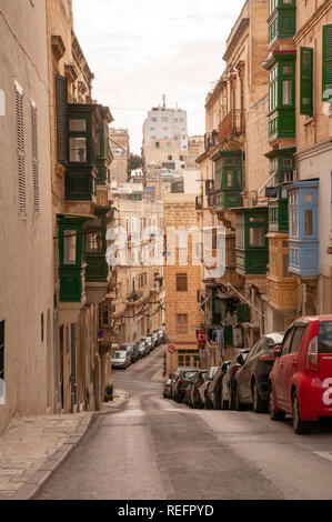 Typische hügelige Seitenstraße in Valletta, der Hauptstadt von Malta, mit dem traditionellen, geschlossenen Holzbalkons. Stockfoto