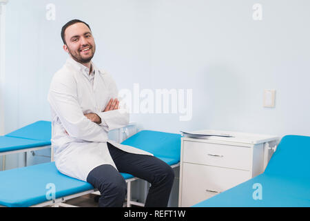 Portrait der junge lächelnde Mann in uniforme in der Nähe von Massageliegen Stockfoto