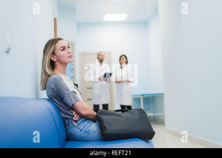 Frau warten an einem Krankenhaus Flur für einen Test Ergebnisse. Nervös. Ärzte, die sich in den Hintergrund. Stockfoto