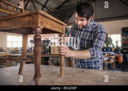 Woodworker Verschrauben einen Stuhl in seiner Schreinerei Stockfoto