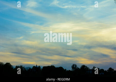 Der Himmel, dessen Wolken in blau und gelb gefärbt, erhebt sich über dem Feld 2019 Stockfoto