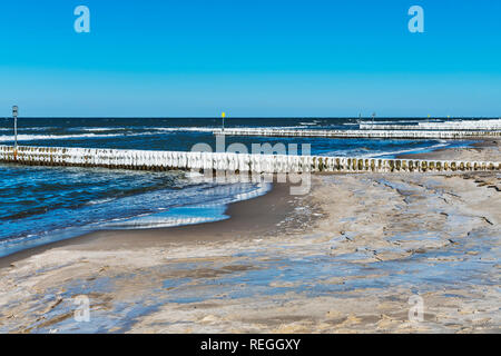 Strand der Ostsee in Kolberg im Winter. Eis bedeckt Buhnen sind im Wasser, Kolberg, Westpommern, Polen, Europa Stockfoto