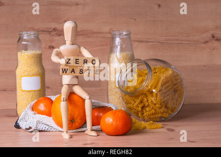 Holz Mann mit Zeichen null Abfall und sitzen auf großen orange Frucht Stockfoto