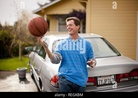 Lächelnd Mitte der erwachsene Mann Ausgleichen einer Basketball auf seinen Finger. Stockfoto