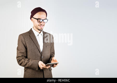 Lächelnd Mann in Tweed Jacket mit einem Tablet-PC. Männliche Person in Hipster style Kleidung verwendet die Technologie, Studio shot auf weißem Hintergrund Stockfoto