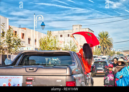 Oued Laou, Chefchaouen, Marokko - November 3, 2018: eine Brünette junge Frau mit langem Haar, Wellen, die die marokkanische Flagge in einem Auto angehoben Stockfoto