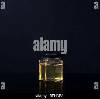 Trüffel Pilz in ein Glas Honig auf schwarzem Hintergrund. Minimalismus in der Komposition. Luxus essen. Freier Platz für Text Stockfoto