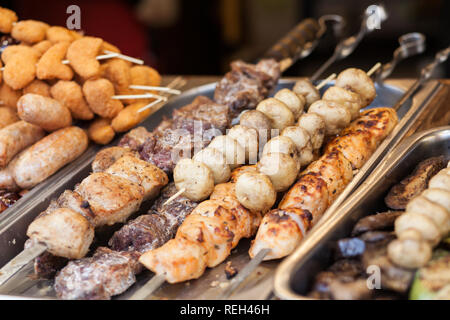 Verschiedene Arten von leckeren Fleisch und Pilzen auf Spieße. Outdoor Küche kulinarische Buffet. Straße Messestand Stockfoto