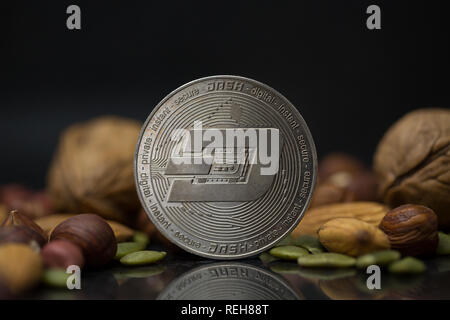 Dash cryptocurrency physischen Münze mit Vielzahl von Muttern, einschließlich Walnüsse, Haselnüsse, Mandeln und Kürbiskerne in dem schwarzen Hintergrund umgeben Stockfoto
