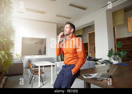 Porträts der Geschäftsmann holding Handy in der Hand und einen Anruf beim Sitzen am Schreibtisch. Stockfoto