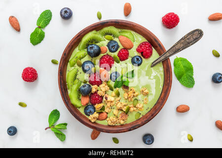 Schüssel mit Matcha Grüntee Smoothie mit frischen Beeren, Nüsse, Samen und Hafer Müsli mit einem Löffel für gesunde vegane, vegetarische Ernährung Frühstück. nach oben anzeigen. Stockfoto