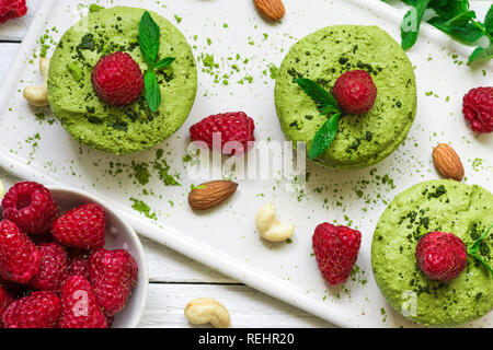 Hausgemachte raw Matcha Pulver Kuchen mit frischen Himbeeren, Minze, Muttern. Gesunde vegane Ernährung Konzept. top View Stockfoto