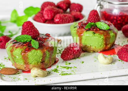 Hausgemachte raw Matcha Pulver Kuchen mit frischen Himbeeren, Marmelade, Minze, Muttern. Gesunde vegane Ernährung Konzept. Nach oben Schließen Stockfoto