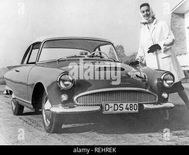 Das Fahren in den 1950er Jahren. Eine junge Frau steht neben einem Auto Auto Union. Sie trägt eine typische 50er Jahre kurze weiße Mantel mit passendem Schal. 1950 s Stockfoto