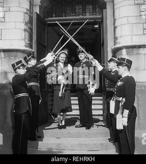 Hochzeitspaar 1950. Das Brautpaar hat die Hochzeitszeremonie beendet und verlässt die Kirche als Ehemann und Ehefrau. Vor den Kirchentüren ehren eine Gruppe von Soldaten in Uniformen das Paar und sie laufen unter ihren gekreuzten Schwertern. Schweden 1950: Kristoffersson Ref. AY102-3 Stockfoto