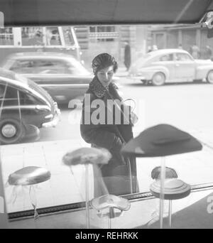 Window Shopping in den 1950er Jahren. Eine Frau steht vor einer Boutique mit der neuesten Mode in Hüte in die Anzeige der Fenster. Schweden 1955. Foto Kristoffersson BS 46-7 Stockfoto