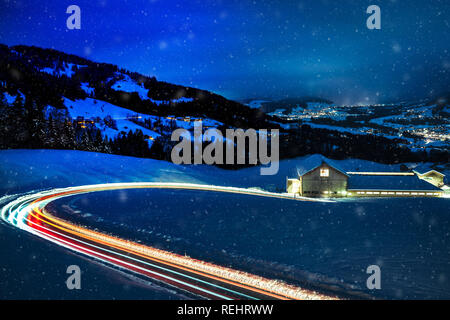 Lange Nacht der Fotografie von Autos durch die schneebedeckten Berge in den Alpen von Österreich fahren ausgesetzt. Stockfoto