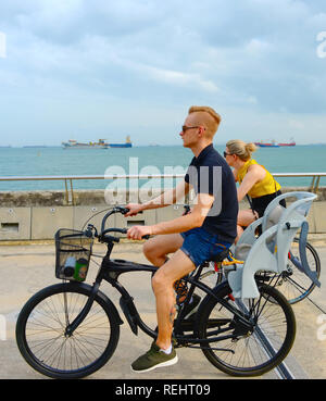 Singapur - Februar 6, 2017: Paar Reiten Fahrräder am Hafen von Singapur. Singapur ist wichtiges Finanzzentrum in Asien Stockfoto