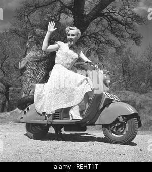 Das Fahren in den 1950er Jahren. Eine junge Frau auf einem Motorroller in Mailand in den 1950er Jahren. Das blonde Mädchen ist glücklich lächelnd auf dem Roller in einem typischen 50er Jahre Kleid angezogen. Foto Kristoffersson Ref BC 22-9 Stockfoto