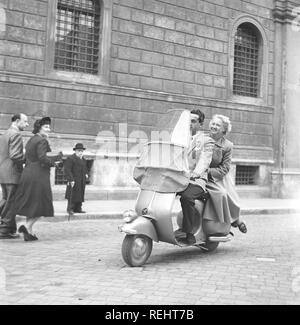 Paar in Italien in den 1950er Jahren. Ein junges Paar auf einem Vespa Roller fahren auf einer Straße in Mailand Italien 1950. Foto Kristoffersson Ref AY 28-7 Stockfoto