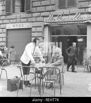 Urlaub in Italien in den 1950er Jahren. Eine junge Frau in einem Café sitzen in einem geschäftigen Mailand Straße. Ein Kellner steht neben ihr höflich und von der Schwedischen blonde Mädchen bezaubert. Mailand Italien 1950. Foto Kristoffersson Ref AY 28-6 Stockfoto