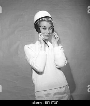 Frau in den 1950er Jahren. Eine junge Frau steht in einer typischen 50s Pullover angezogen. Sie setzt sich auf einen weissen Moped Helm. Foto Kristoffersson ref BZ 8-6. Schweden 1952 Stockfoto