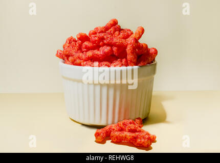 Eine Schüssel der Flamin' Hot Cheetos enthüllt die Spicy Chili Käse Pulver Gewürz, dass Coats die aufgeblasen Maismehl Snack. Stockfoto