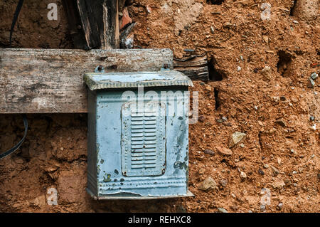 Alte verwitterte Grunge veraltete Metalldose post Briefkasten auf Adobe Lehm Mauer von verlassenen ländlichen Country House closeup Stockfoto