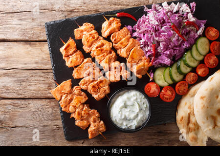 Close-up Hähnchenspieße mit frischem Salat, Joghurt Sauce und pita Brot auf einer Schiefertafel board. horizontal oben Ansicht von oben Stockfoto