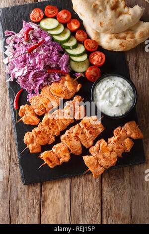 Close-up Hähnchenspieße mit frischem Salat, Joghurt Sauce und pita Brot auf einer Schiefertafel. Vertikal oben Ansicht von oben Stockfoto
