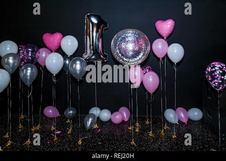 Festliche foto Bereich mit Dekorationen aus einer großen aufblasbaren Nummer eins mit weißen, rosa und grau Ballons, freier Speicherplatz. Schwarzer Hintergrund Kugeln, Rosa, w Stockfoto