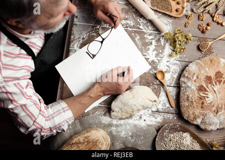 Alte Bäcker schreiben Alte - Rezept in Bäckerei Notebook vom Brot umgeben Stockfoto