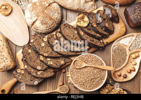 Ganzen Körnern Mehrkornbrot, ganz und geschnitten, enthält Samen isoliert auf Schwarz Stockfoto
