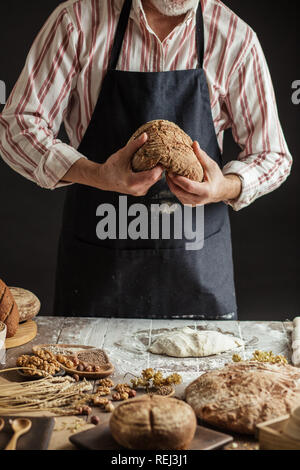 Nicht erkennbare Bäcker hält frisch gebackene rustikalen organische Laib Brot in der Hand Stockfoto