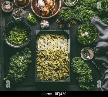 Grüne frische Pasta mit Pesto, Grünkohl kochen Vorbereitung auf dunklen Tisch mit Zutaten und Küchengeräte. Gesunde Mahlzeit. Detox Gemüse. Reinigen Sie e Stockfoto