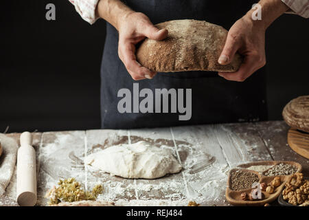 Nicht erkennbare Bäcker hält frisch gebackene rustikalen organische Laib Brot in der Hand Stockfoto