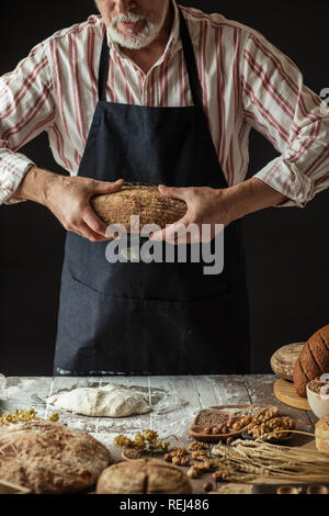 Nicht erkennbare Bäcker hält frisch gebackene rustikalen organische Laib Brot in der Hand Stockfoto