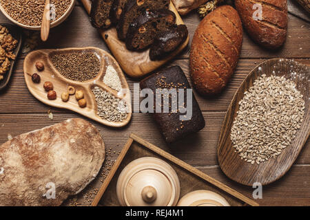 Ganzen Körnern Mehrkornbrot, ganz und geschnitten, enthält Samen isoliert auf Schwarz Stockfoto