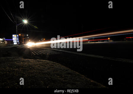 Schnell fahrendes Auto auf einer Landstraße in der Nacht an einem viel befahrenen Highway, im Staat New York genommen Stockfoto