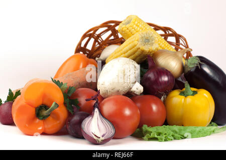 Pilze und eine Vielzahl von frischem Gemüse in einem Weidenkorb. isoliert auf einem weißen Stockfoto