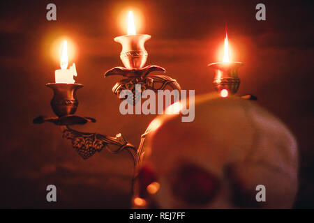 Kerze anzünden von Schädel mit Kerze und Bücher auf dem Schreibtisch aus Holz dekorieren für Halloween Theme mit kopieren. Noch immer leben Bild und selektiven Fokus Stockfoto