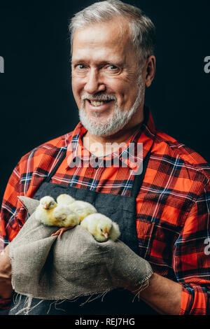 Mann in Schwarz Schürze und kariertes Hemd mit einem Geschenk für seine Enkelin Stockfoto