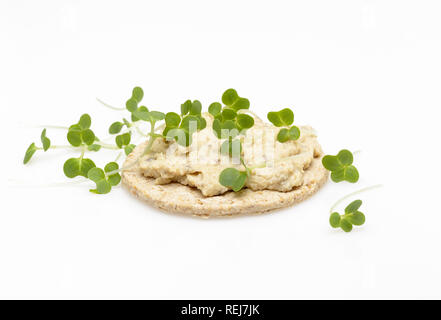 Glutenfreie oatcake gekrönt mit Hummus oder Stil Houmous und Kresse auf weißem Hintergrund Stockfoto