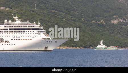 Riesige Passagier Kreuzfahrt und eine kleine private Motoryacht mit einem Hubschrauberlandeplatz in die Bucht von Kotor Stockfoto