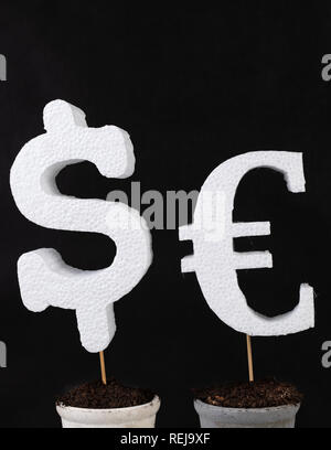 Dollar und Euro Symbol eingebettet in einen Topf mit frischen schwarzen Boden. Kennzeichnung der Welt Währung. Der dunkle Hintergrund. Stockfoto