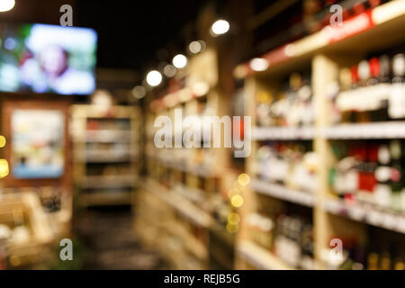Verschwommenes Bild von Regalen mit bunten Flaschen Wein. Stockfoto